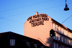 Un mural cu textul „Gunoiul unui om, comoara altuia” pe un perete din București.