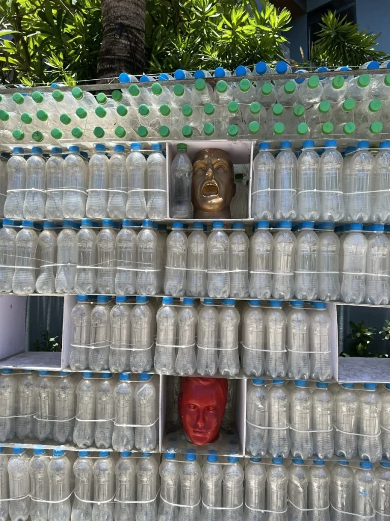 Structură artistică realizată din sticle de plastic, cu măști colorate integrate.