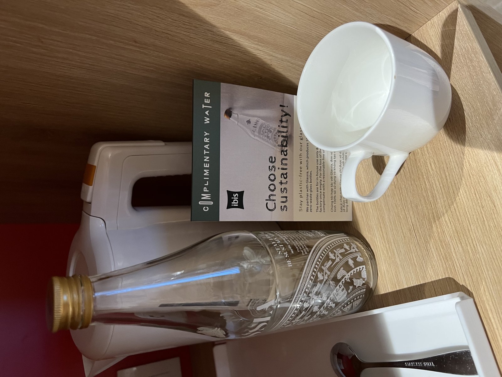 Water bottle and cup on a wooden surface promoting sustainable tourism.