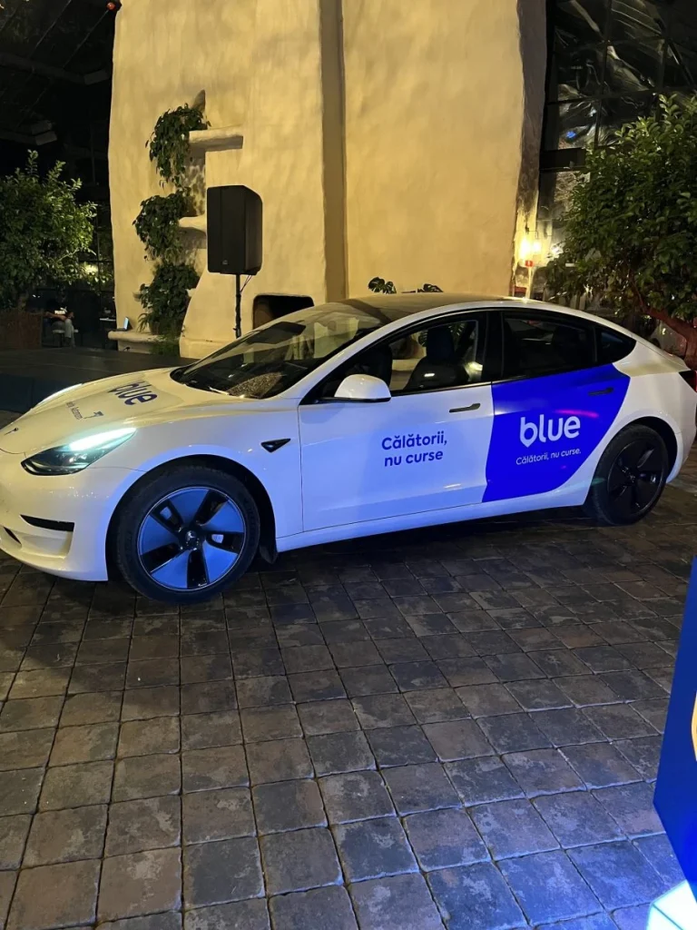 Blu ride-sharing car with logo on the body inside an elegant venue.