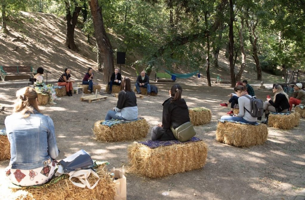People sitting on hay bales at Trifoi Fest, listening to discussions about the environment.