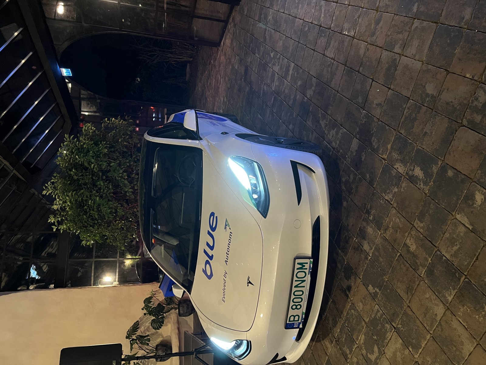 Mașină de ride sharing Blu parcată într-un spațiu elegant, cu iluminare nocturnă.