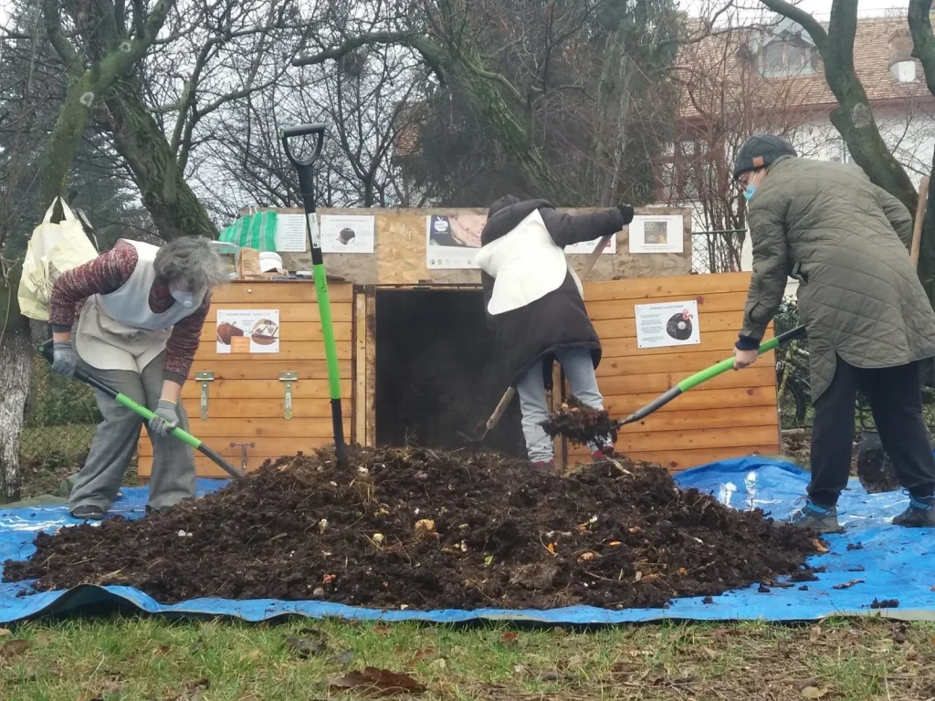 Three individuals engage in community composting, working with a pile of compost.