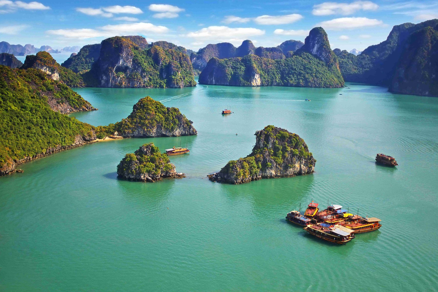 Scenic view of green islands in clear water, with anchored boats under a clear sky.