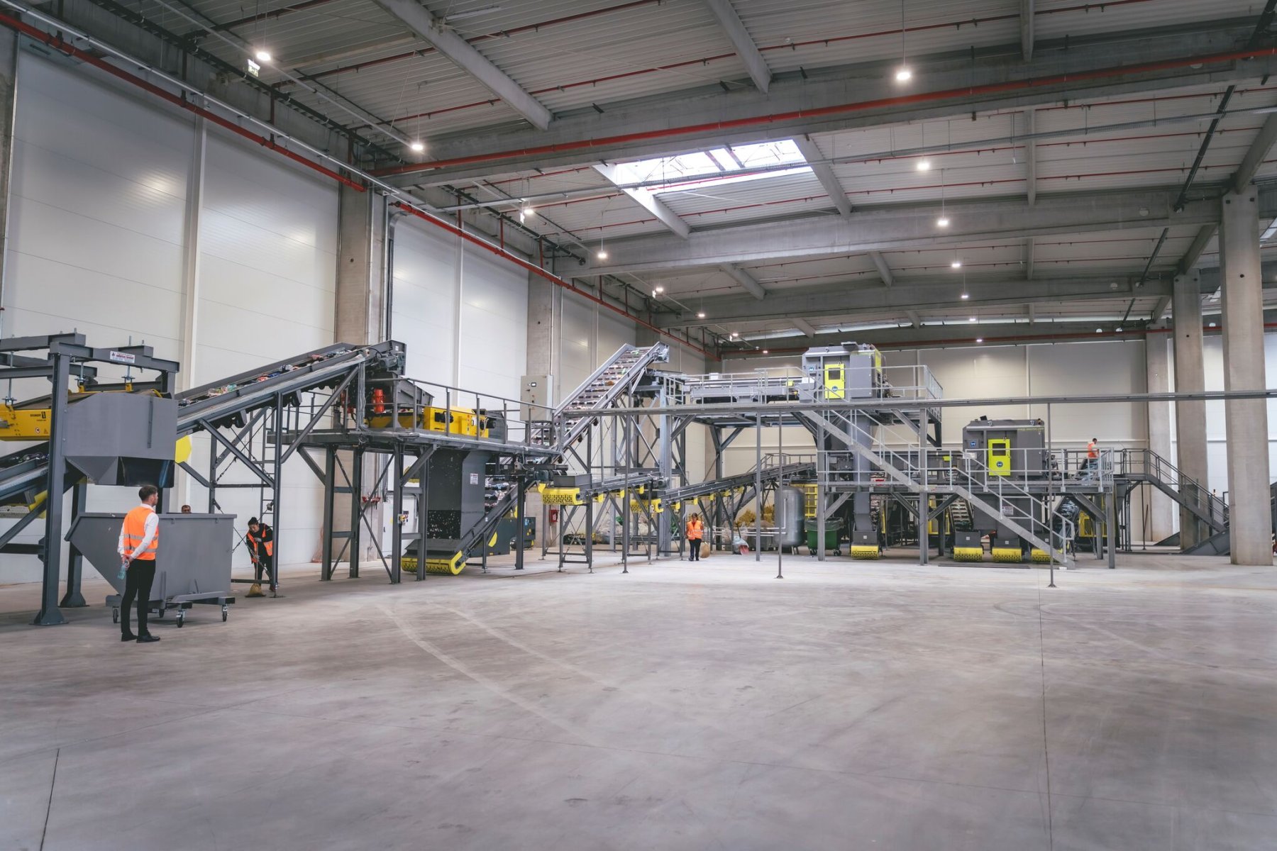 Interior of a recycling facility with sorting lines and workers.